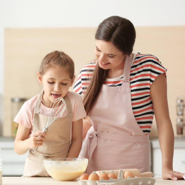 Mother and her daughter making dough at table in kitchen